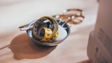 Measuring tape and scissors on wooden table.
