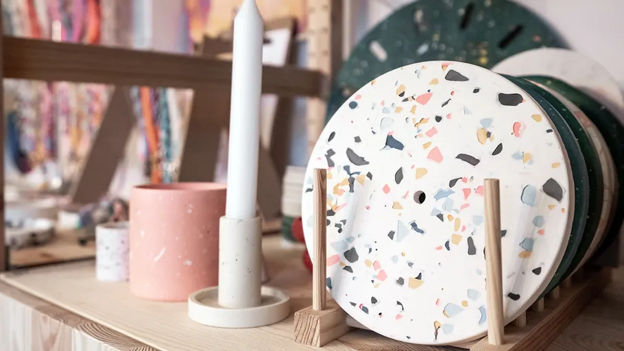 Colorful terrazzo plates displayed on wooden stand.