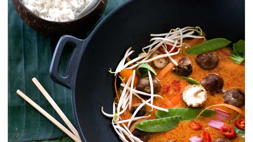 Soup with vegetables in a black bowl.