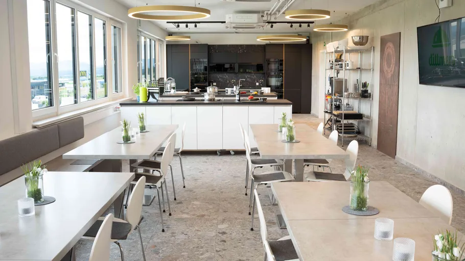Moderne Küche mit Tischen und Stühlen, helle Beleuchtung.