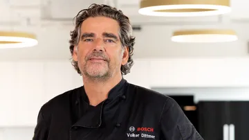 Chef in black uniform in modern kitchen.