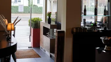Restaurant entrance with open glass door, counter nearby.