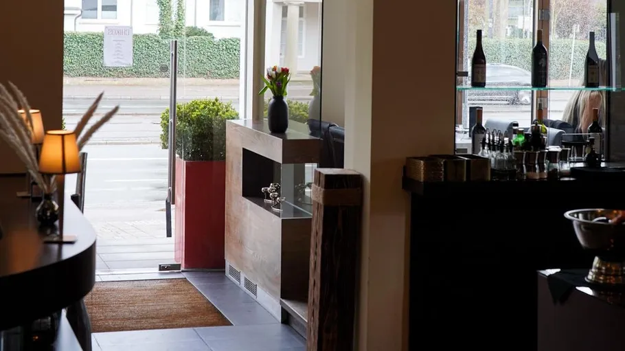 Restaurant-Eingang mit offener Glastür, Theke in der Nähe.