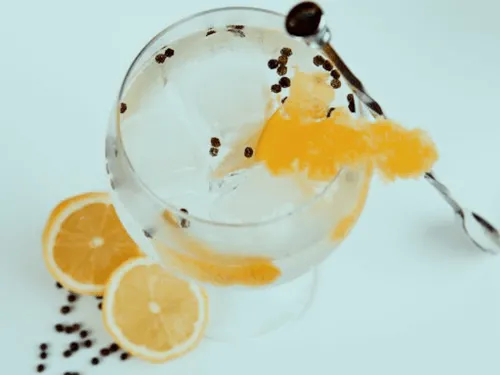 Glas mit Getränk, Eis und Zitronenscheiben, helles Ambiente.