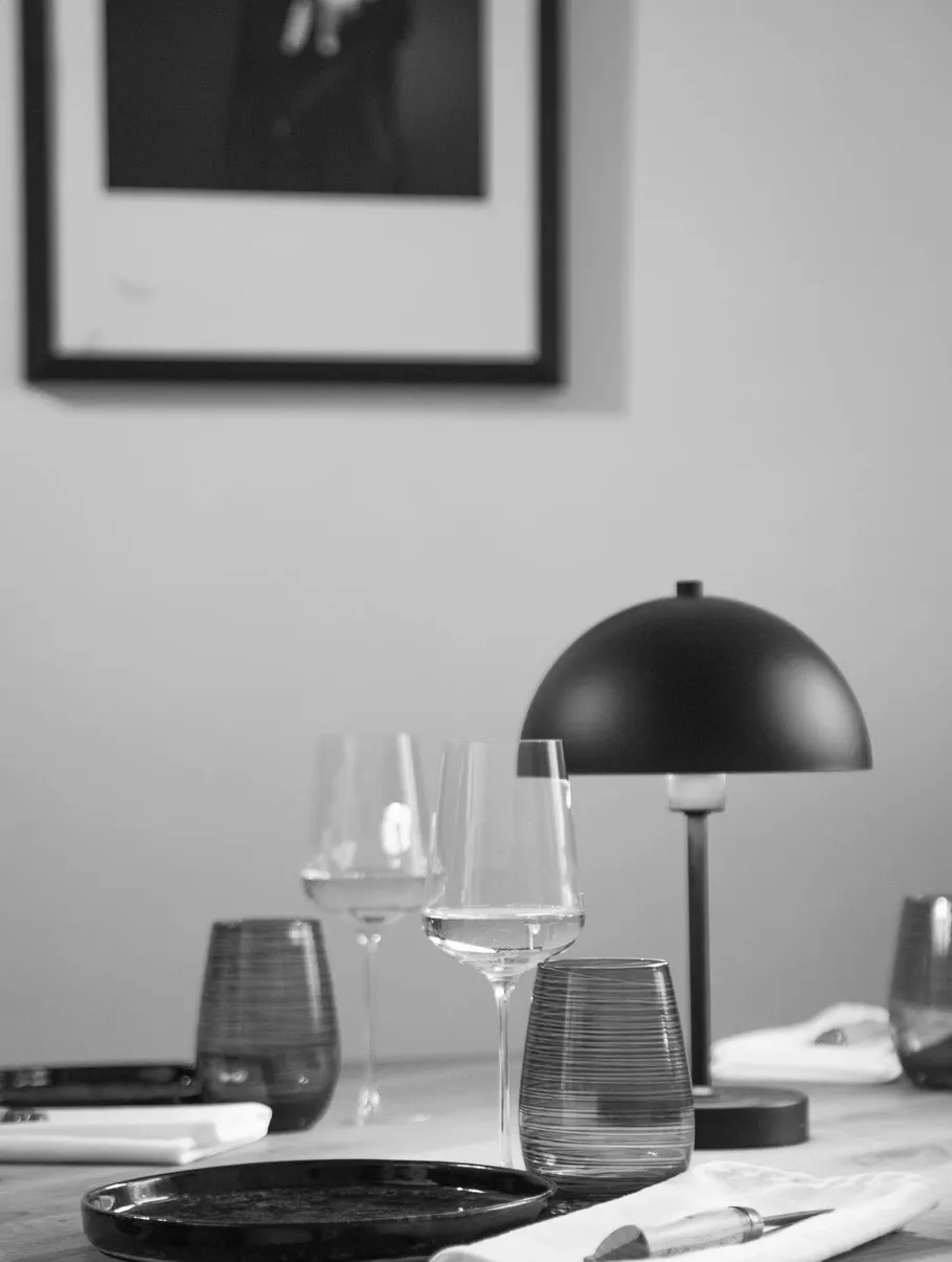 Tisch mit Gläsern, Tellern und Lampe drinnen.