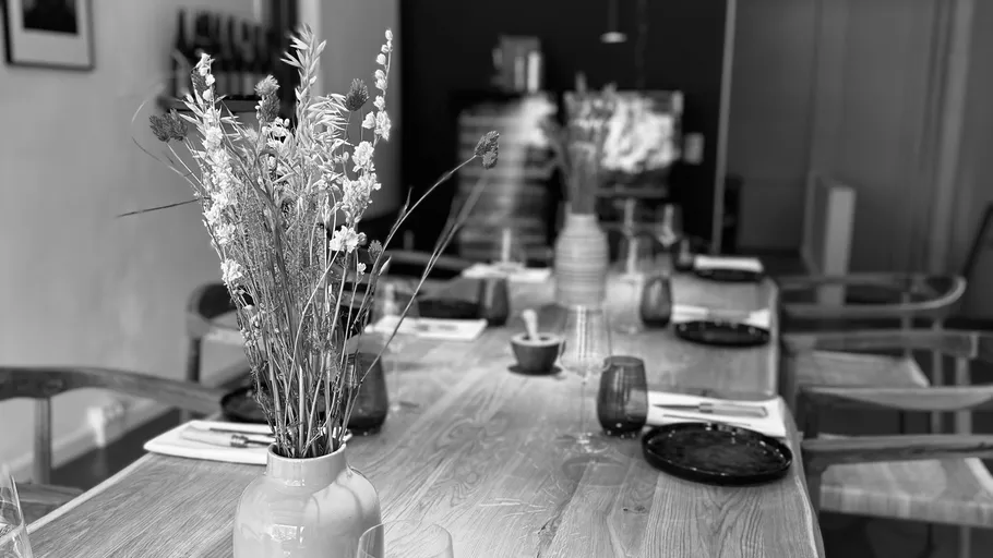 Tisch mit Blumen gedeckt mit Tellern und Gläsern.