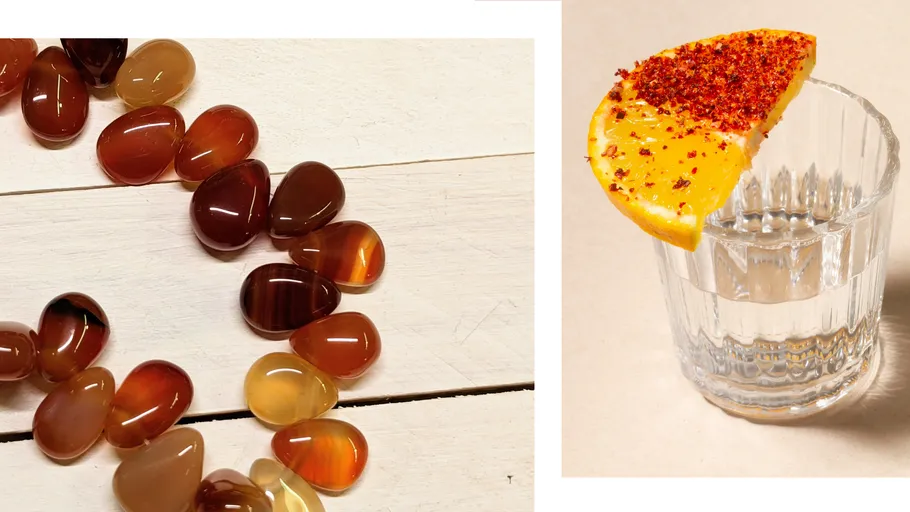 Polierte Steine auf Holz; Schnapsglas mit Orange.