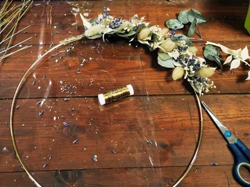 Wire hoop with attached dried flowers on table.
