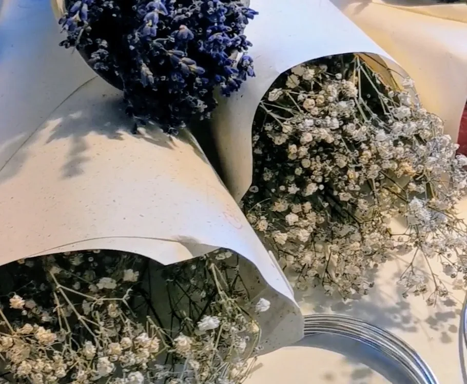 Dried flowers wrapped in paper on a table.
