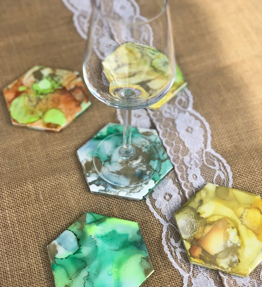 Glass on colorful hexagonal coasters, burlap surface.