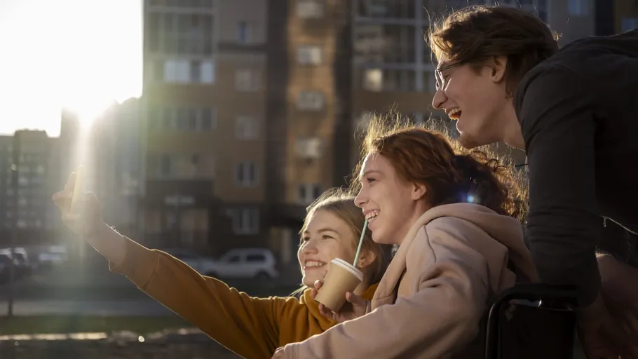 Drei Freunde machen ein Selfie im Freien, lächelnd.