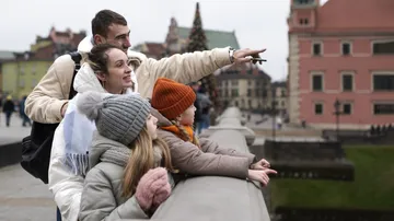 Familie zeigt interessiert, Stadtansicht im Hintergrund.