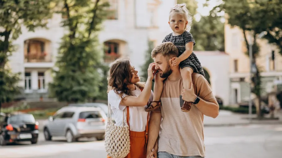 Familie spaziert in sonniger städtischer Straße.