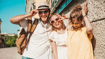 Three people posing joyfully outdoors on a sunny day.