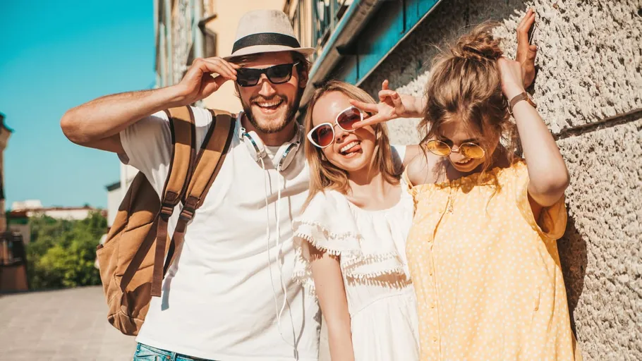 Three people posing joyfully outdoors on a sunny day.