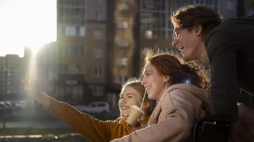Three friends take selfie in urban setting.