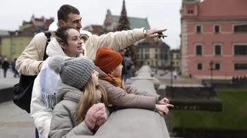 Family on bridge pointing at cityscape.