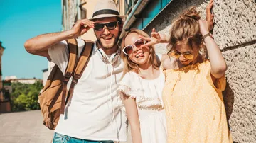 Three friends smiling in summer clothing outdoors.