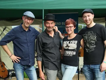 Four people pose smiling in front of a music stage.