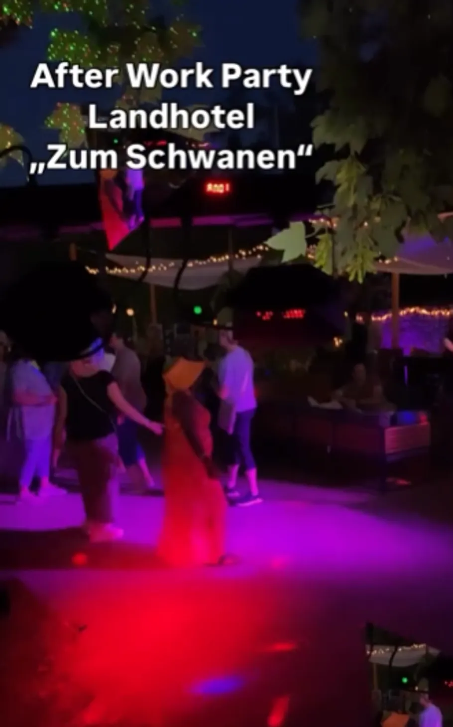 Personen tanzen nachts unter Neonlichtern.