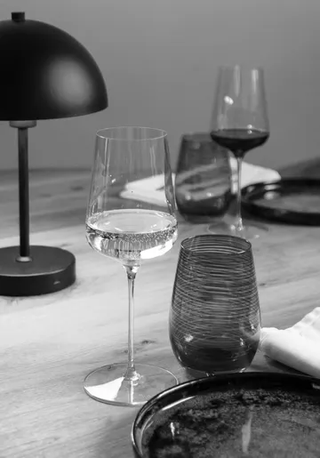 Wine glass and lamp on wooden table.