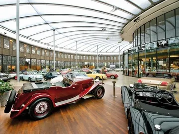 Red classic cars are in a modern car museum.