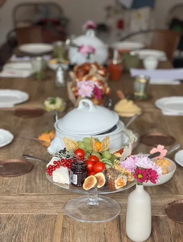 Tisch mit Geschirr und dekorativen Blumen gedeckt.