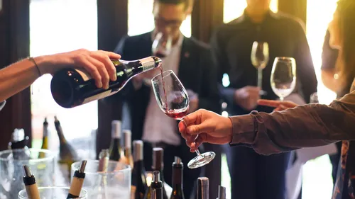 Person gießt Rotwein bei einer Weinprobe ein.