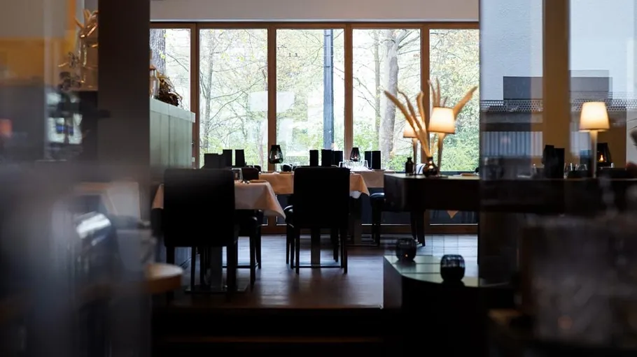Restaurant interior with tables and large windows.