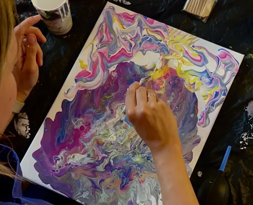 Person painting colorful abstract art on canvas.