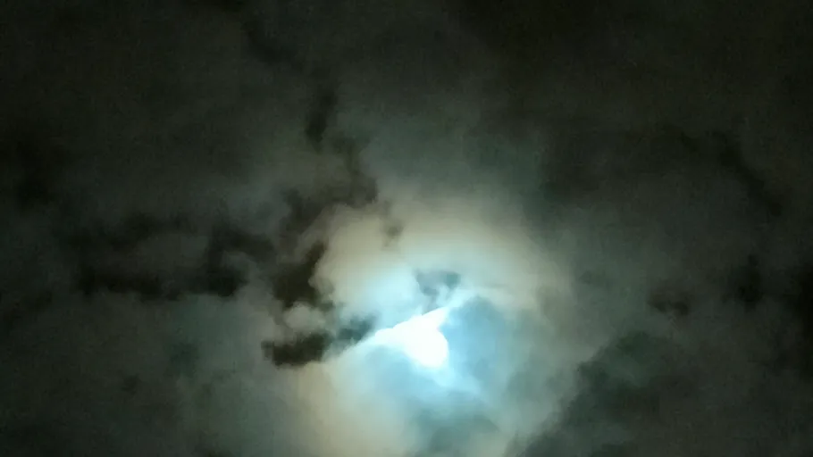 Helles Mondlicht durch wolkigen Nachthimmel.