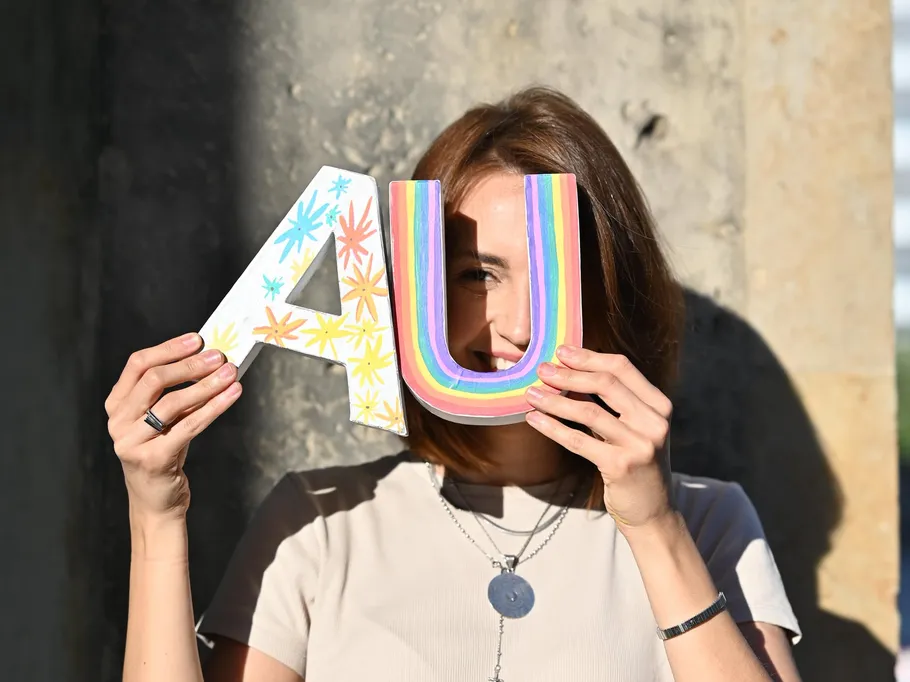 Woman holding colorful letters near face.