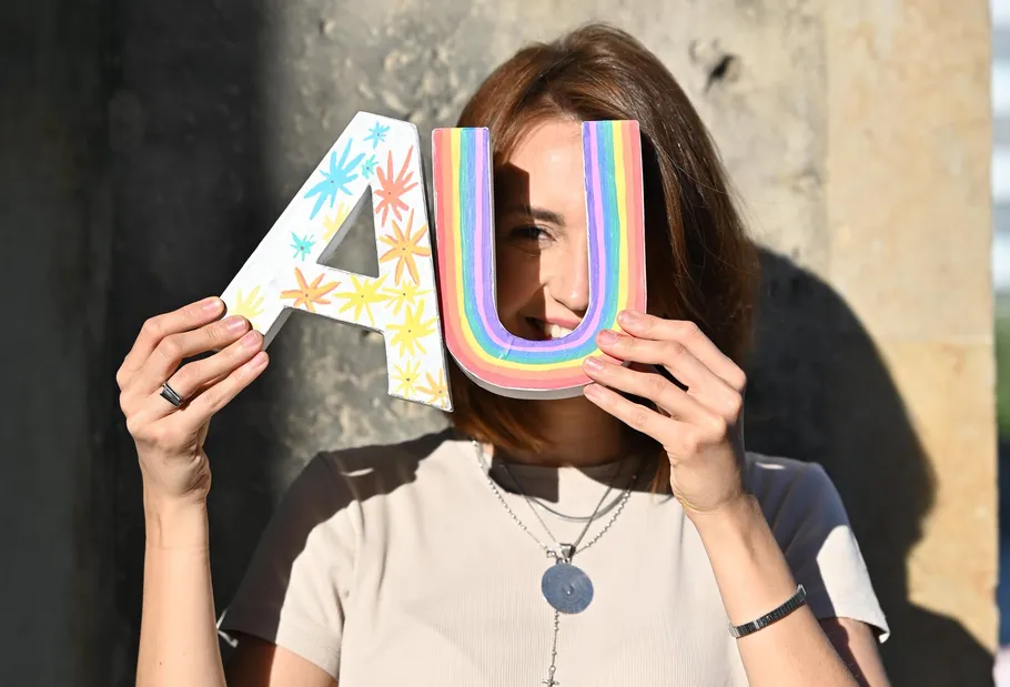 Woman holding colorful letters near face.