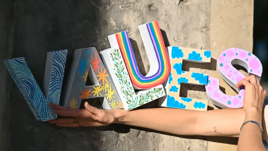 Hands hold colorful letters spelling 'VALUES'.