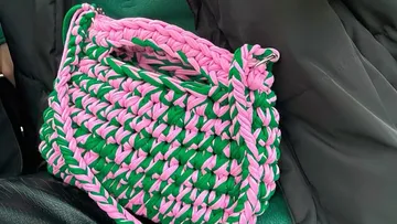 Woven pink and green handbag on a seat.