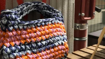 Colorful woven bag on outdoor wooden table.