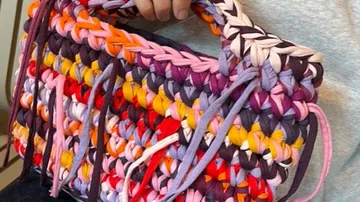 Bunte gehäkelte Handtasche von Person gehalten.