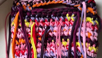 Buntes gehäkeltes Textil mit hängenden Fäden.