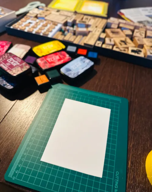 Blank paper on cutting mat surrounded by stamps.
