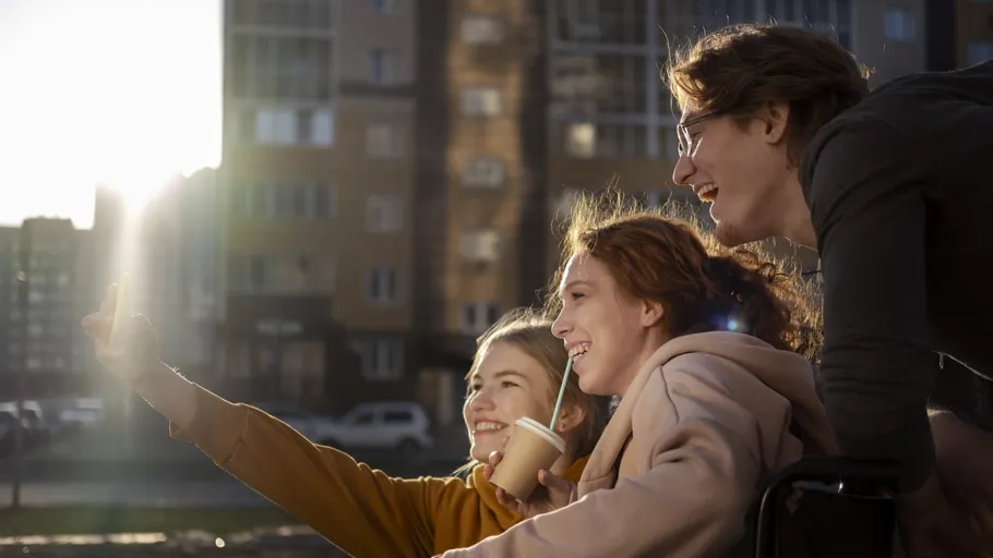 Drei Freunde machen ein Selfie im Freien, lächelnd.
