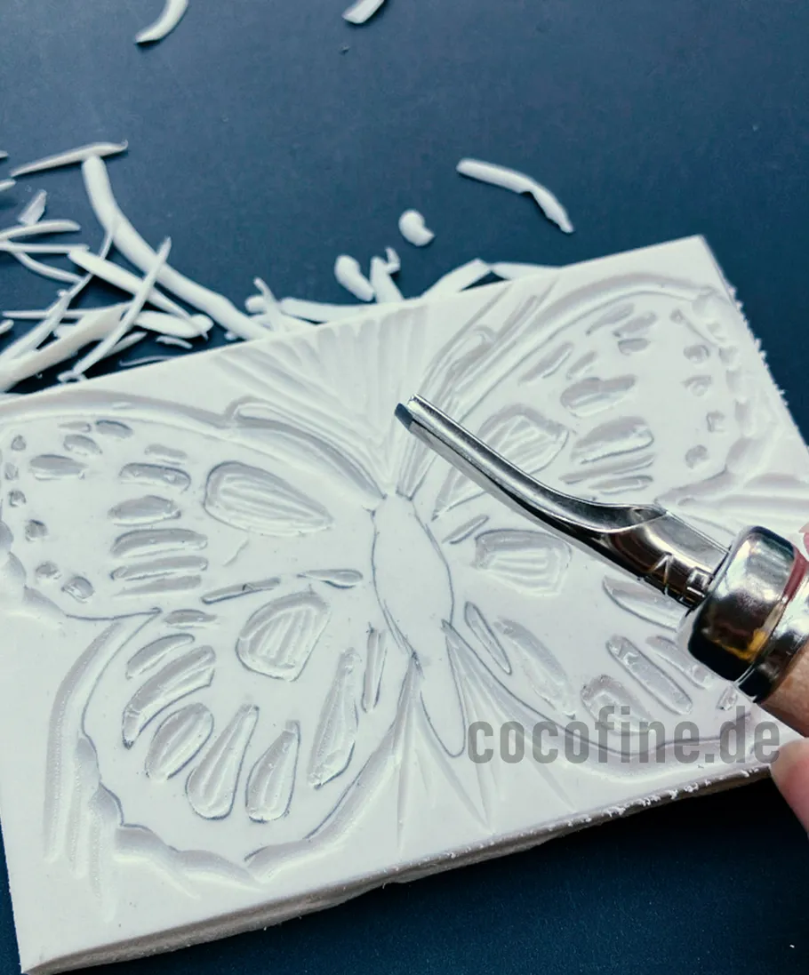 Linocut tool carving butterfly design.