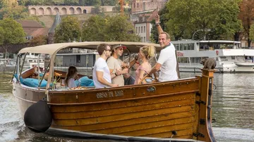 Group on wooden boat enjoying river view.