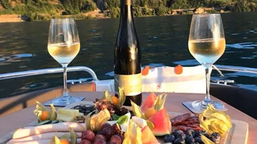 Wine and snacks on boat with lake view.