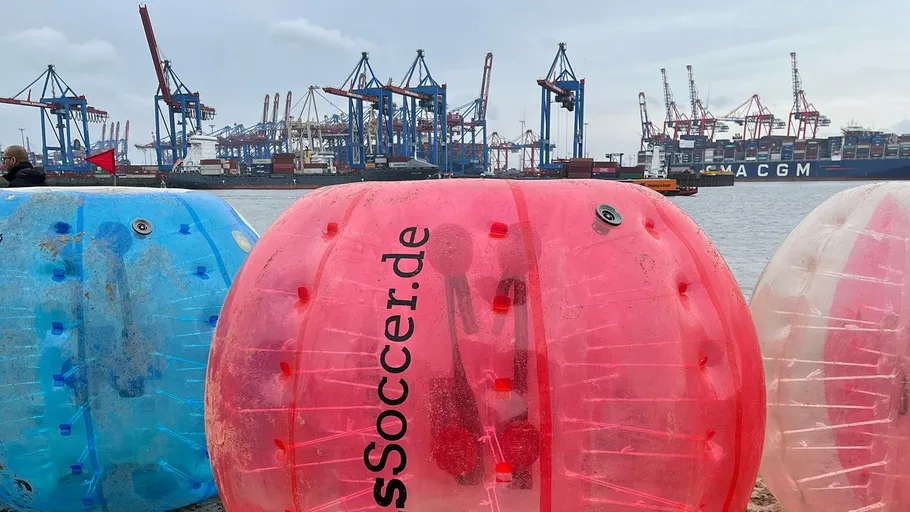 Inflatable bubbles on beach near shipping port.