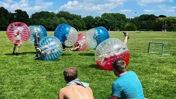 Personen spielen Bubble-Fußball im Park.