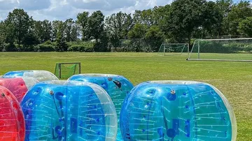 Aufblasbare Bälle auf Rasen nahe Fußballtoren.