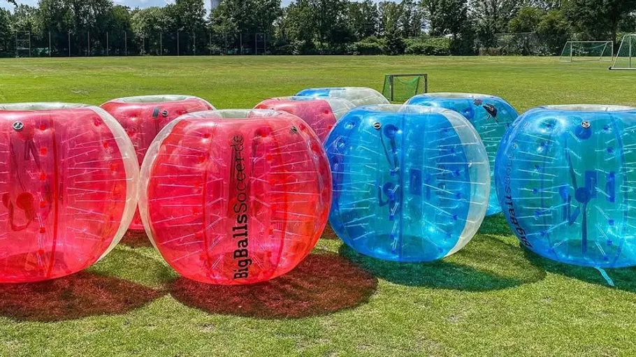 Inflatable balls on grassy soccer field.