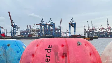 Krane und Container in einem geschäftigen Hafen.