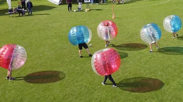 Menschen in Bällen spielen Fußball im Freien.