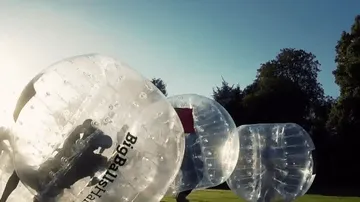 Menschen in aufblasbaren Bällen im Freien spielen.